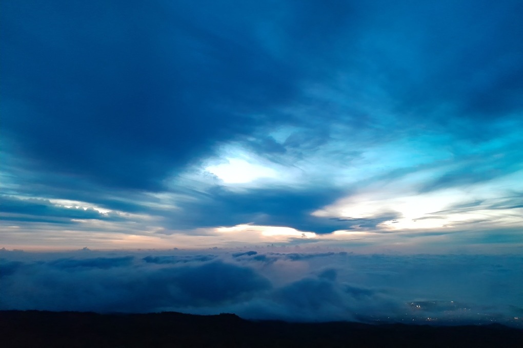 coucher de soleil au-dessus des nuages à La Réunion, avec un ciel bleu intense et une lumière mystique au Piton Maïdo