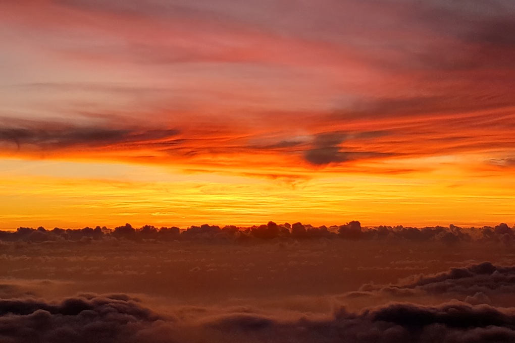 coucher de soleil intense à La Réunion, avec un ciel rouge orangé et un horizon sombre au-dessus d’une mer de nuages