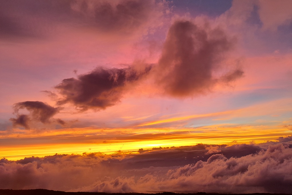 coucher de soleil coloré à La Réunion, avec des nuages rosés et un ciel orange lumineux au-dessus de l’océan