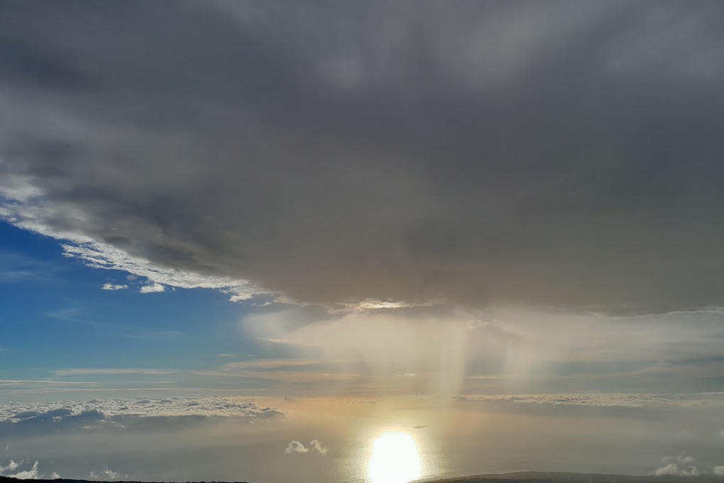 coucher de soleil orageux à La Réunion, avec des nuages sombres et une lumière filtrée se reflétant sur l’océan