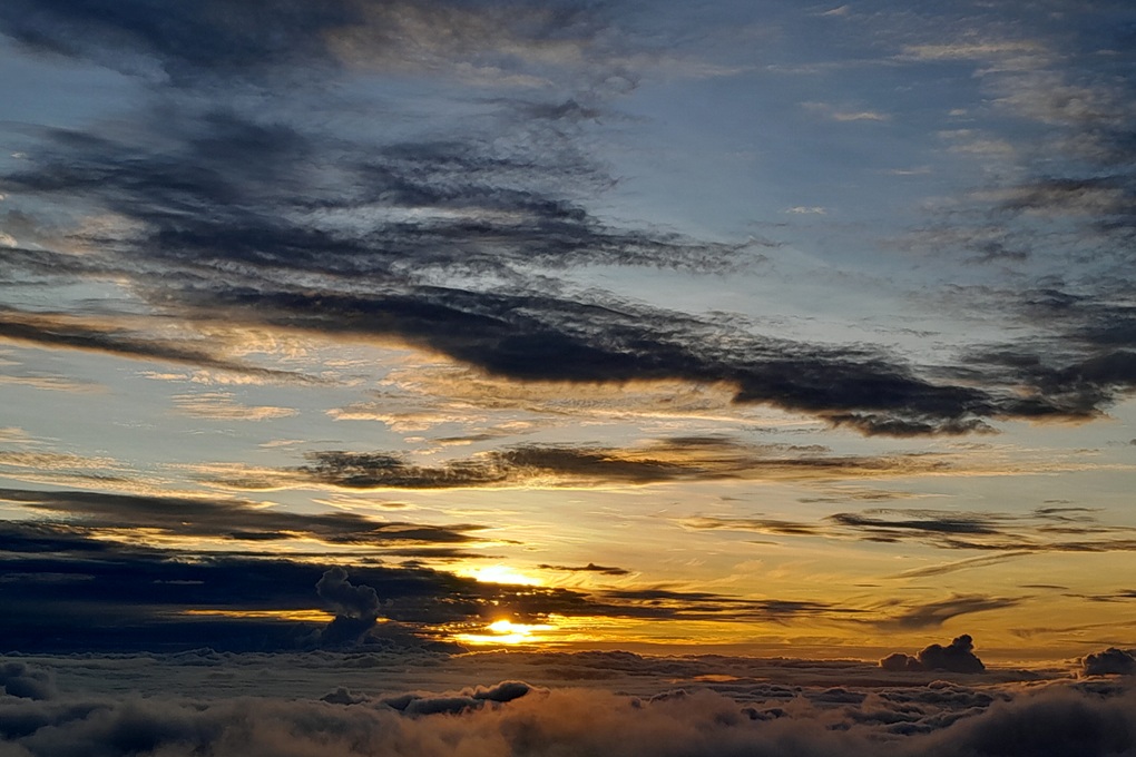 coucher de soleil doré à La Réunion, avec un ciel nuageux et une lumière chaude au-dessus des nuages