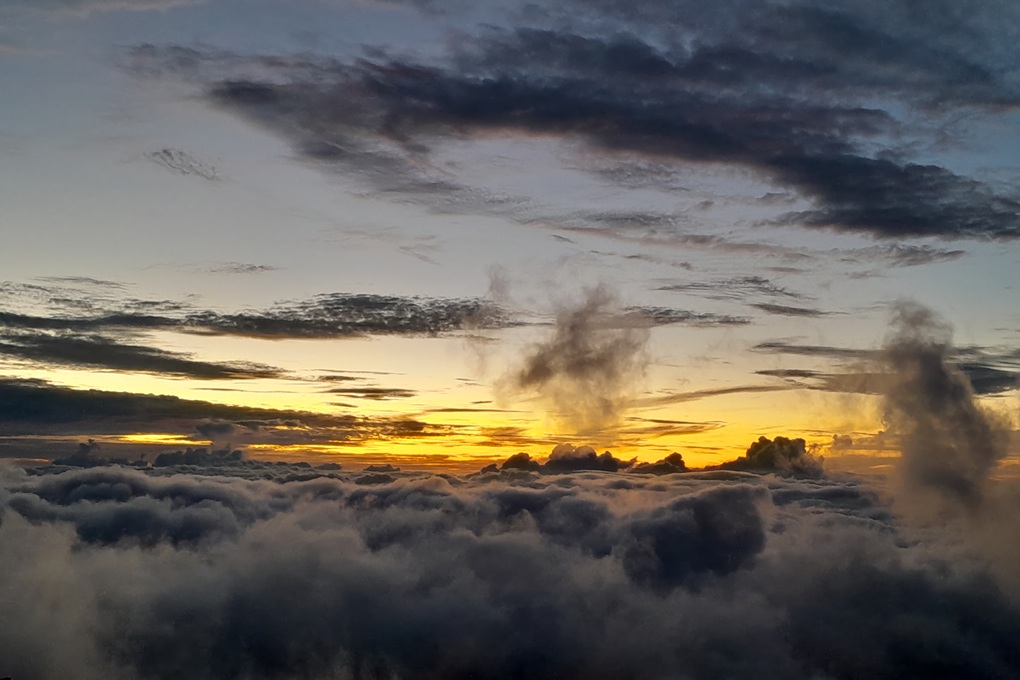 coucher de soleil dramatique à La Réunion, avec des nuages sombres et une lumière dorée au-dessus d’une mer de nuages