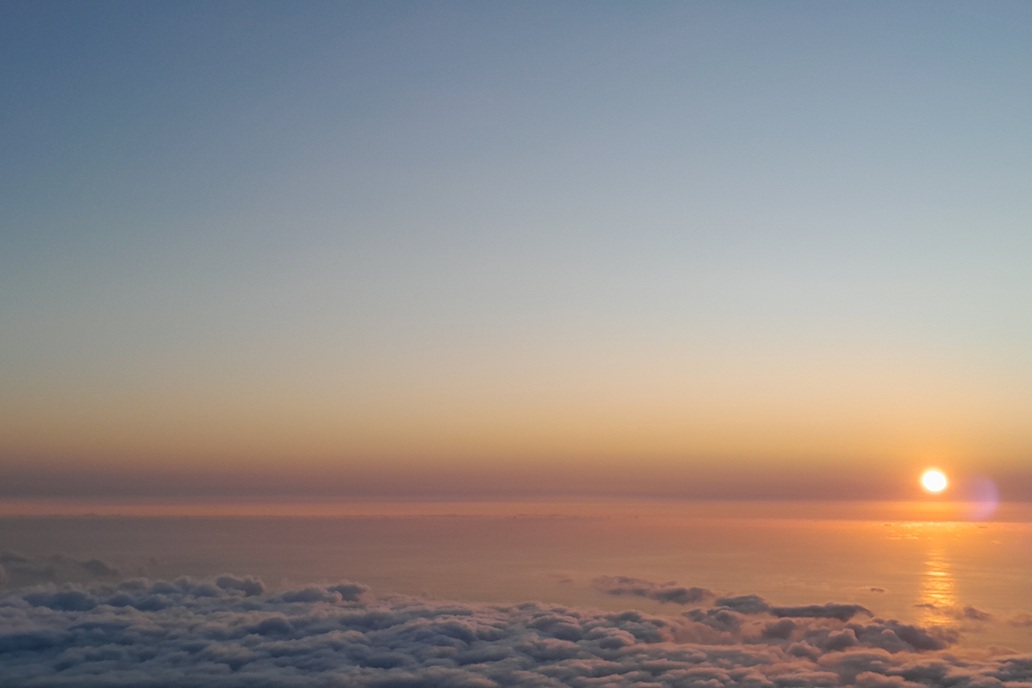 coucher de soleil à La Réunion, avec un horizon dégagé et des reflets dorés sur l’océan au-dessus d’une mer de nuages