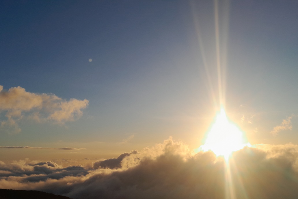 coucher de soleil à La Réunion, avec un soleil éclatant au-dessus des nuages et des rayons lumineux dans un ciel clair