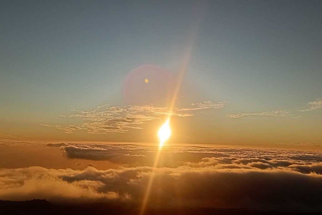 coucher de soleil éclatant à La Réunion, avec un soleil brillant et des rayons lumineux au-dessus des nuages