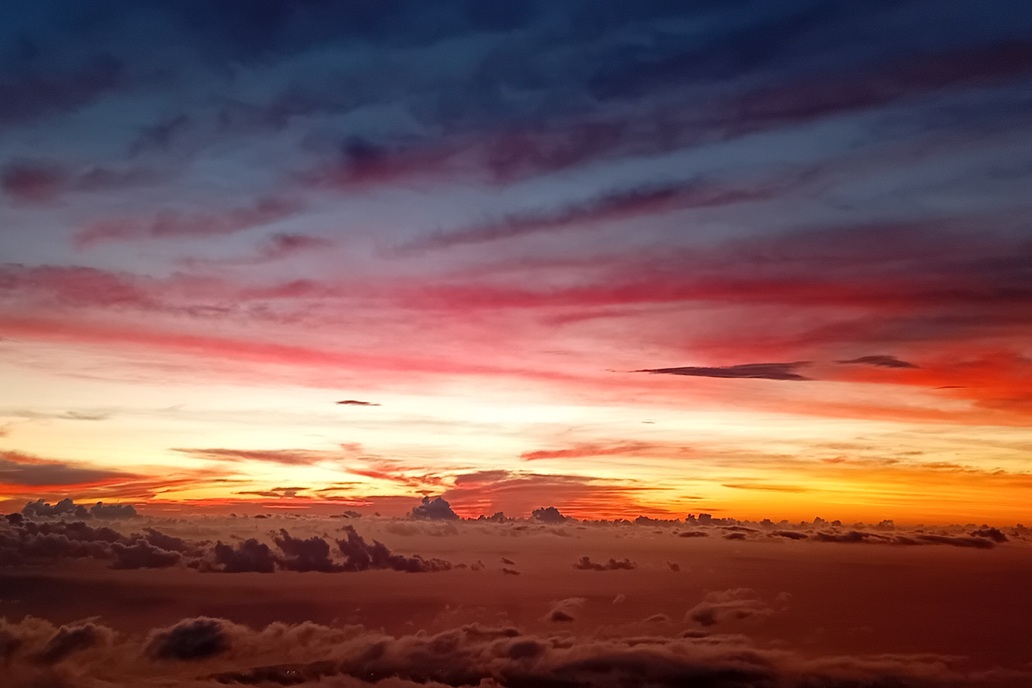 coucher de soleil spectaculaire à La Réunion, avec un ciel rouge et violet et des nuages contrastés au-dessus de l’océan
