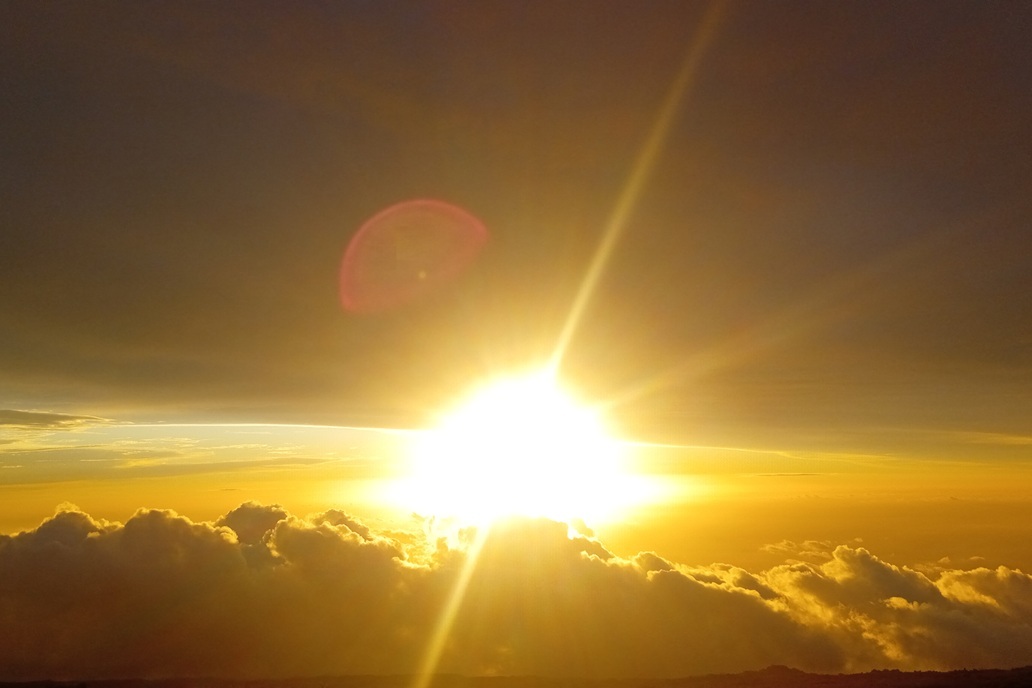 coucher de soleil éclatant à La Réunion, avec un soleil intense au-dessus des nuages et une lumière dorée rayonnante