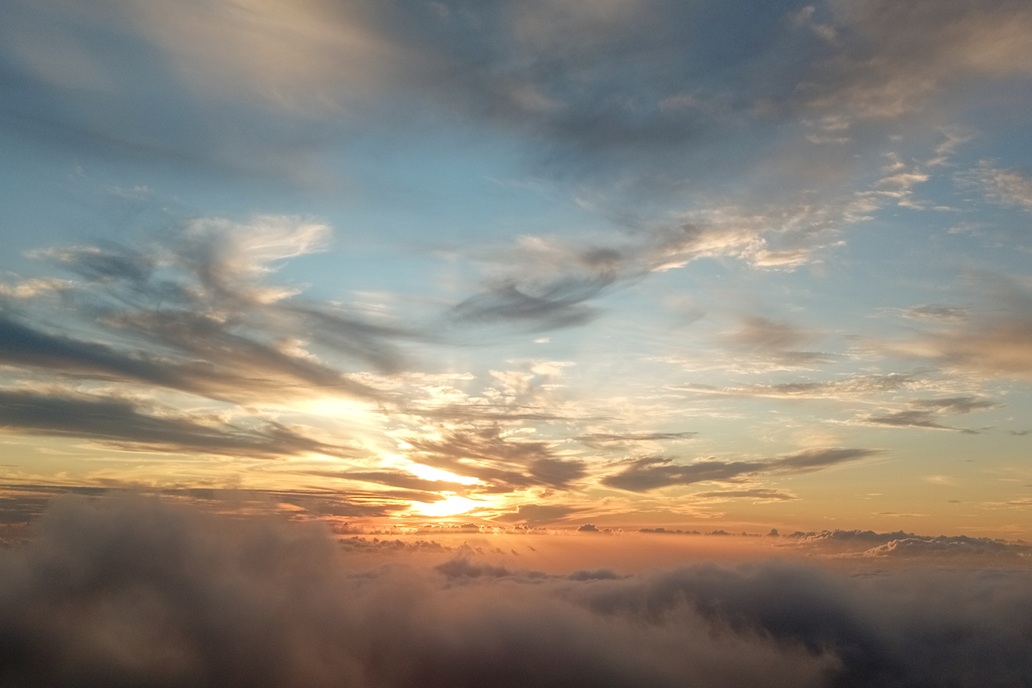 coucher de soleil doré au-dessus d’une mer de nuages à La Réunion, avec un ciel orange et une atmosphère apaisante
