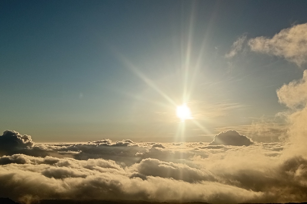 coucher de soleil à La Réunion, avec un horizon dégagé et des reflets dorés sur l’océan au-dessus d’une mer de nuages