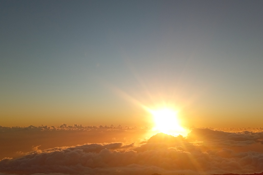 coucher de soleil doré à La Réunion, avec un soleil diffus au-dessus d’une mer de nuages et un ciel apaisant