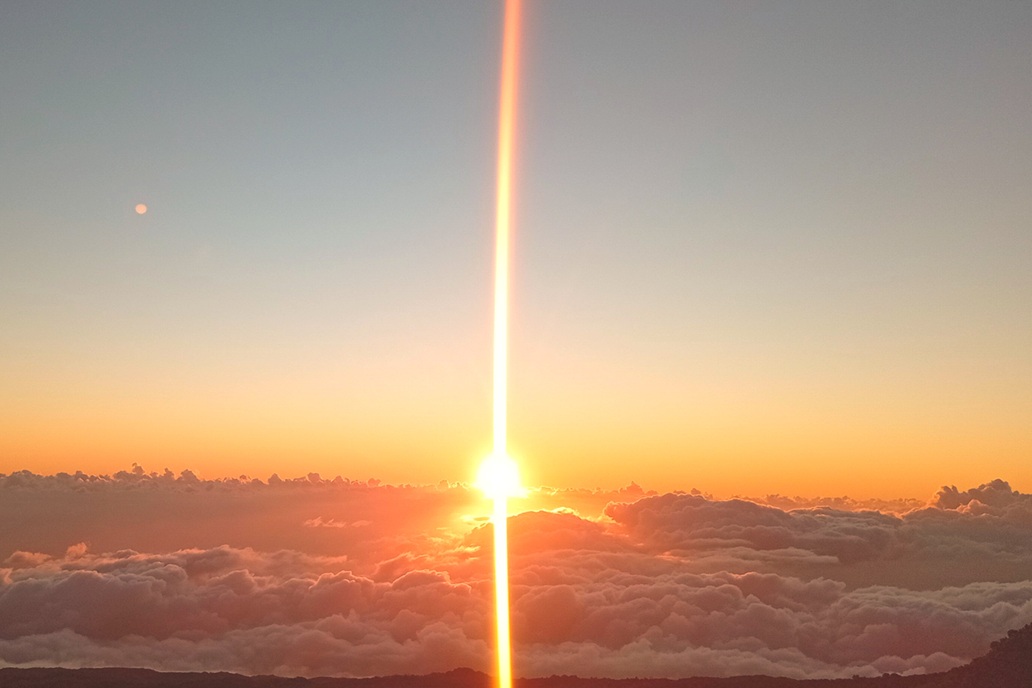 coucher de soleil à La Réunion, avec un soleil perçant les nuages et une brume colorée au-dessus de l’océan