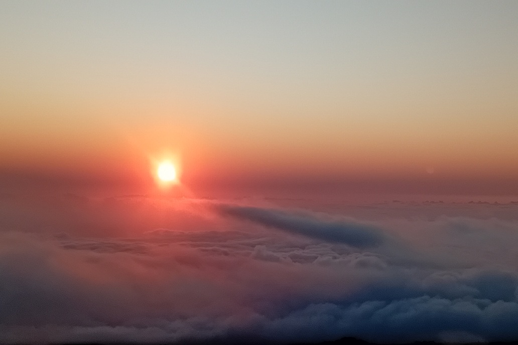 coucher de soleil intense à La Réunion, avec une lumière rouge orangée et des nuages enveloppants au-dessus de l’océan