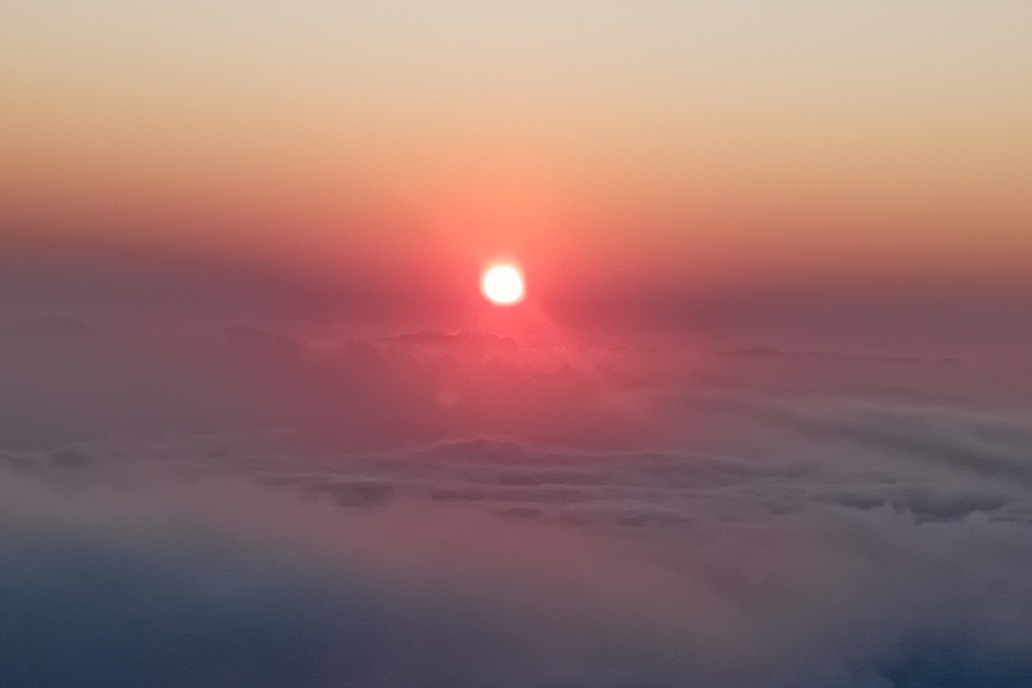 coucher de soleil minimaliste à La Réunion, avec le soleil disparaissant à l’horizon au-dessus d’une mer de nuages calme