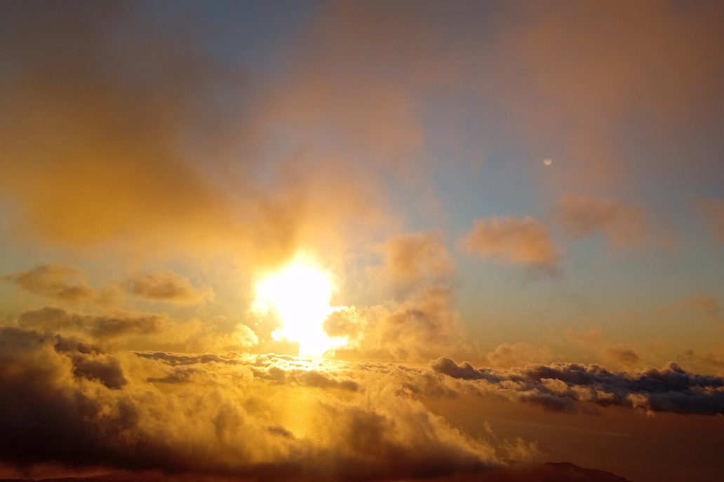 coucher de soleil chaleureux à La Réunion, avec des nuages dorés et une lumière douce au-dessus de l’océan Indien