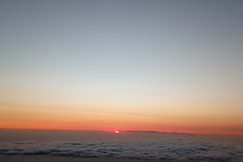 coucher de soleil minimaliste à La Réunion, avec le soleil disparaissant à l’horizon au-dessus d’une mer de nuages calme