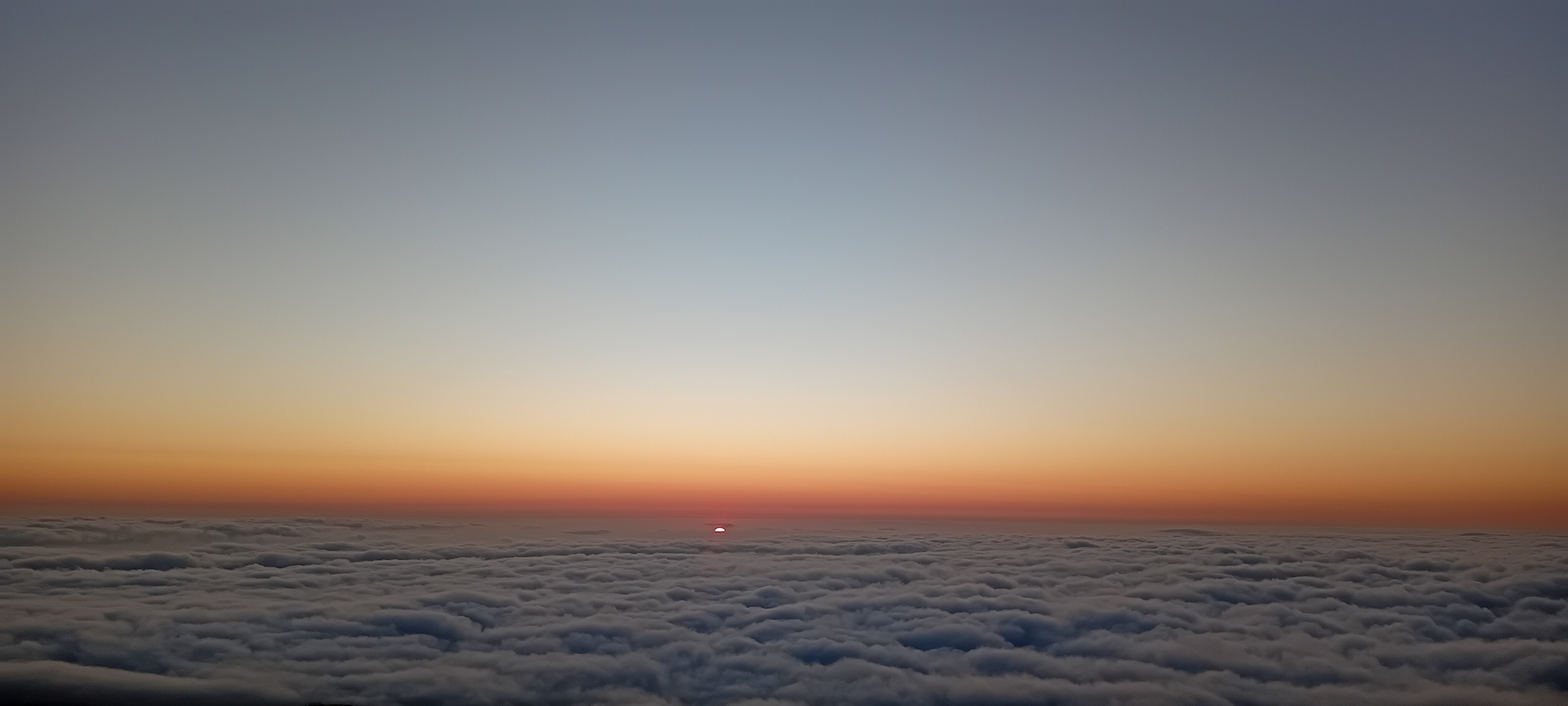 coucher de soleil lumineux à La Réunion, avec un soleil rayonnant entre les nuages et un ciel partiellement couvert