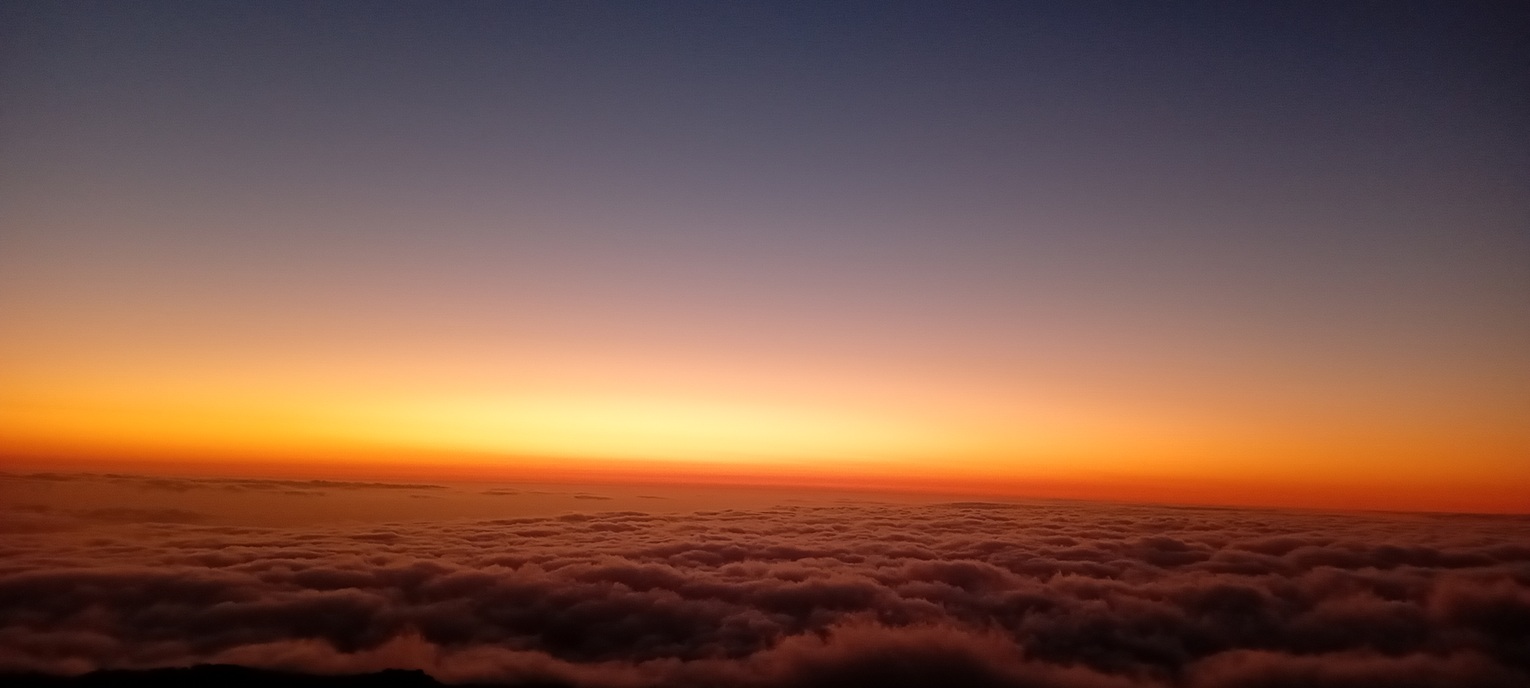 coucher de soleil minimaliste à La Réunion, avec un horizon orange intense et une mer de nuages uniforme