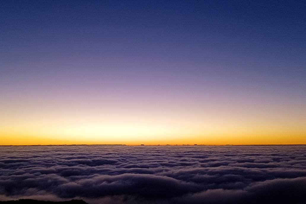 coucher de soleil minimaliste à La Réunion, avec un horizon orange et une mer de nuages sombre sous un ciel dégagé