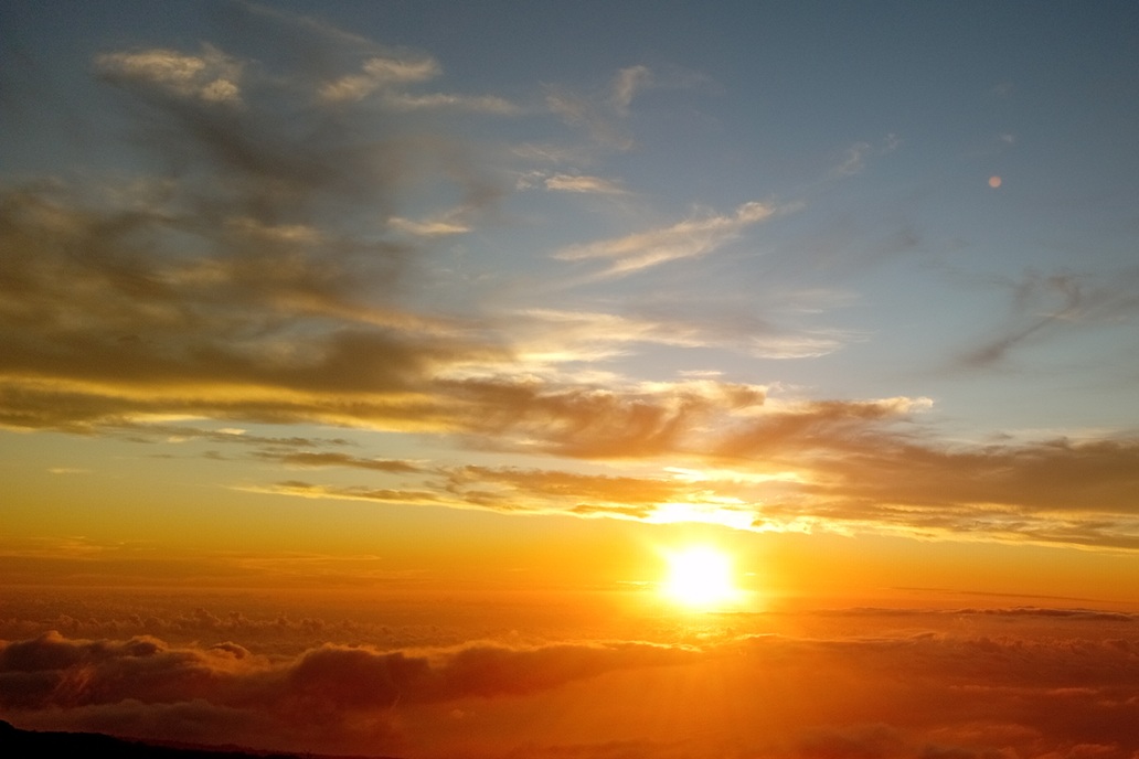 coucher de soleil panoramique à La Réunion, avec un ciel coloré et une lumière dorée sur une mer de nuages