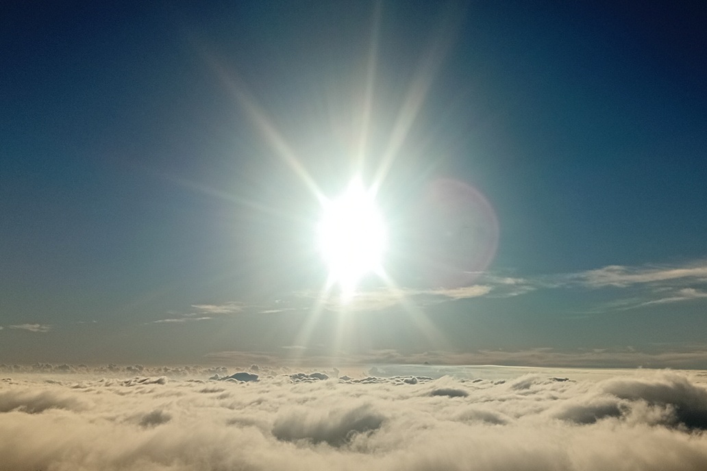 coucher de soleil minimaliste à La Réunion, avec le soleil disparaissant à l’horizon au-dessus d’une mer de nuages calme