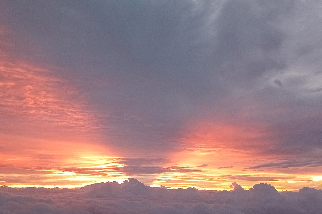 coucher de soleil doux à La Réunion, avec un ciel pastel rose et gris et des nuages étendus au-dessus de l’horizon