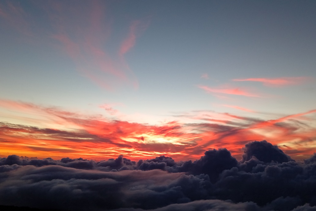 coucher de soleil vibrant à La Réunion, avec un ciel rouge intense et des nuages volumineux au-dessus de l’océan
