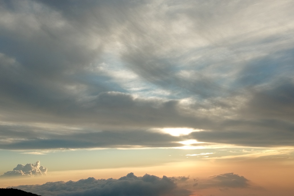 coucher de soleil voilé à La Réunion, avec le soleil caché derrière les nuages et une lumière douce sur l’horizon