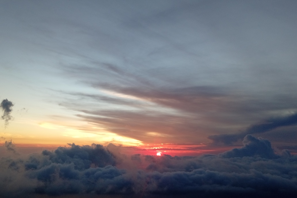 coucher de soleil chaleureux à La Réunion, avec des nuages dorés et une lumière douce au-dessus de l’océan Indien
