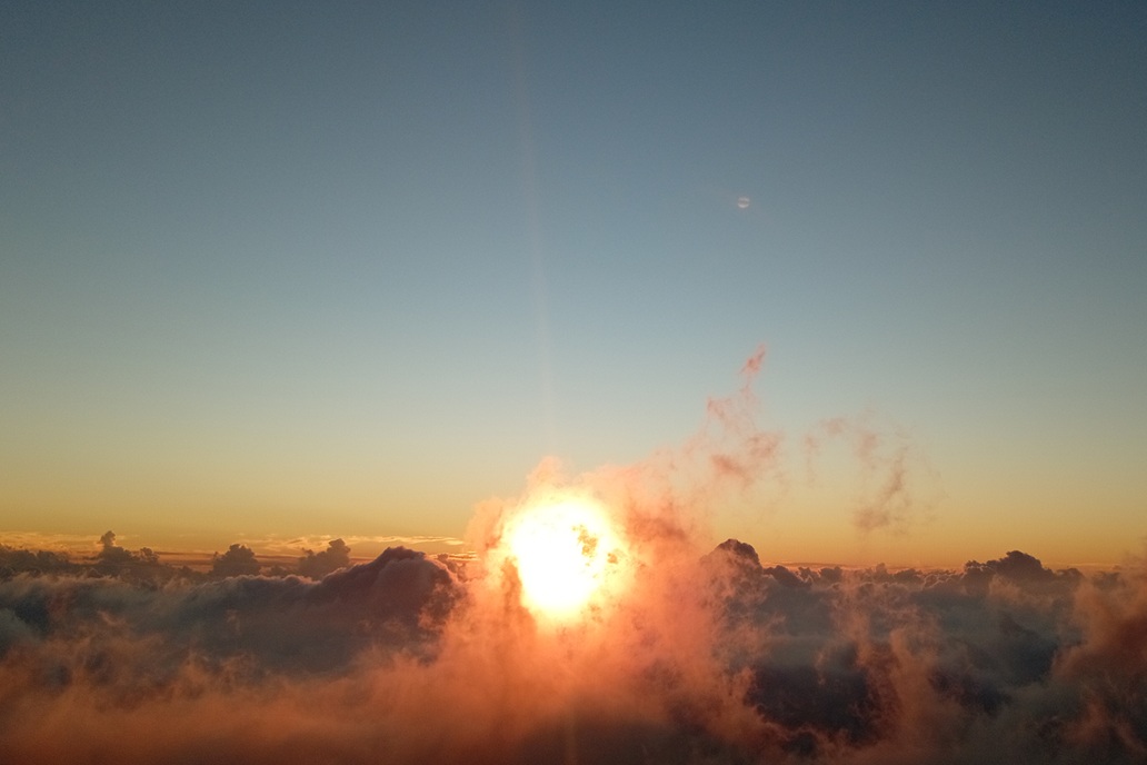 coucher de soleil à La Réunion, avec un soleil perçant les nuages et une brume colorée au-dessus de l’océan